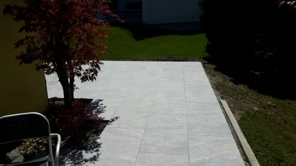 Terrasse mit Gartenplatten neben einem Ahorn