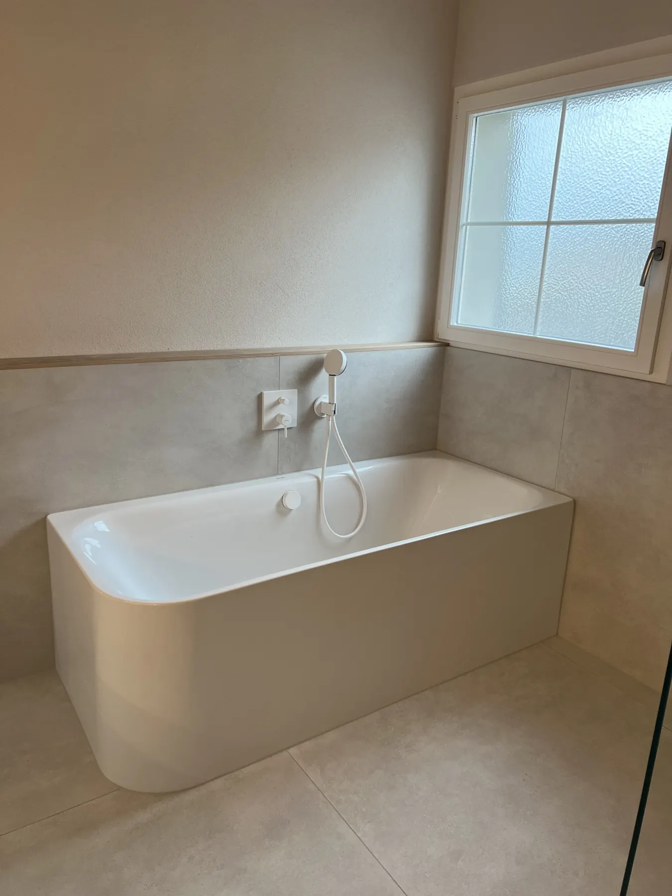 Badewanne im Bad mit hellen Platten