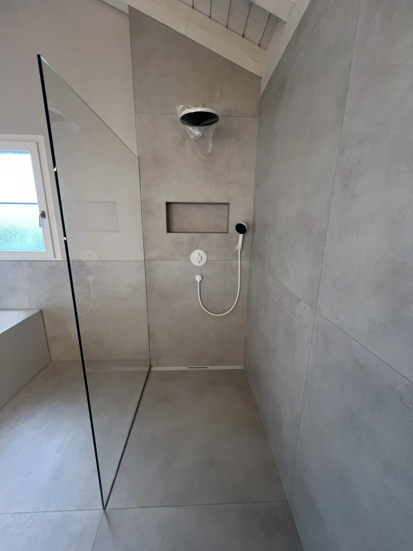 Dusche mit hellen Grossformatplatten und Glaswand