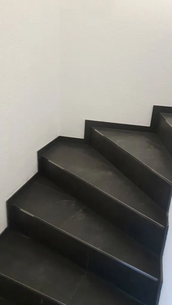Treppe mit dunklen Platten und Handlauf